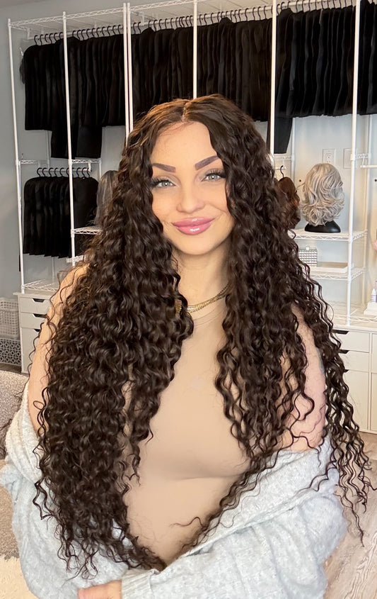Woman holding a long curly wig in a hair product store.