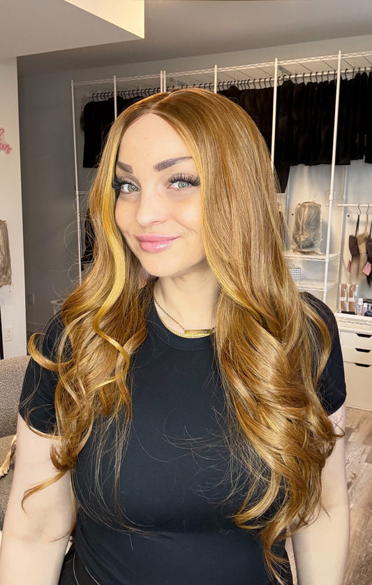 Woman with long wavy hair in a room with clothing racks and furniture.