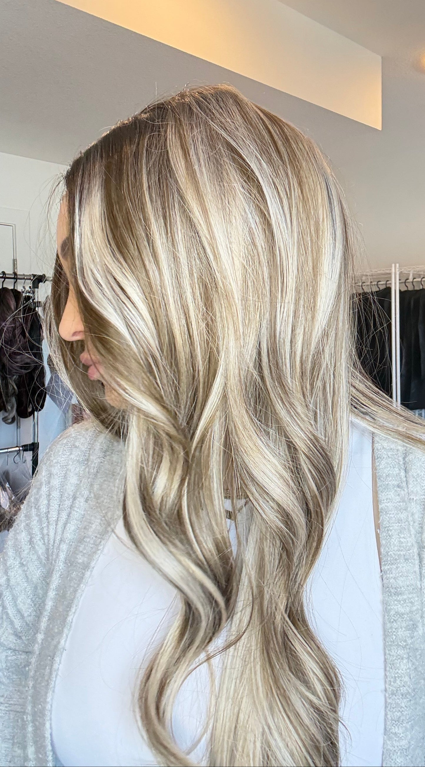 Person with long, wavy blonde hair in a salon setting