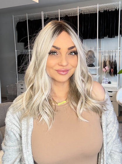 Woman with blonde hair in a room with clothing racks in the background