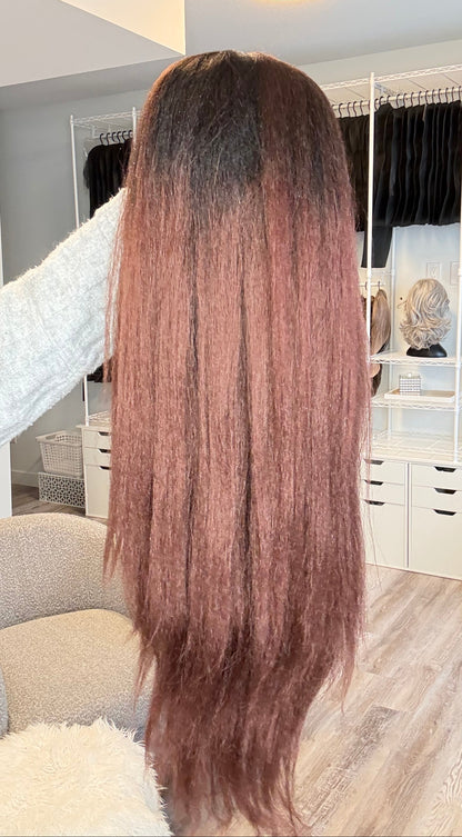Long brown hair styled in a salon setting with mirrors and chairs.