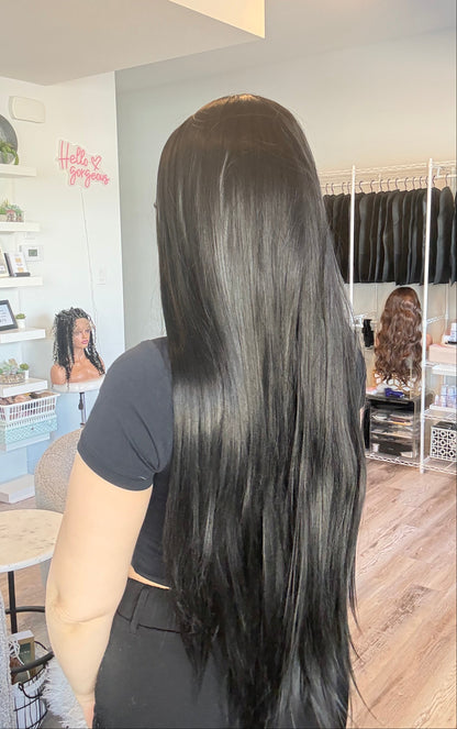 Person with long, straight black hair in a salon setting.