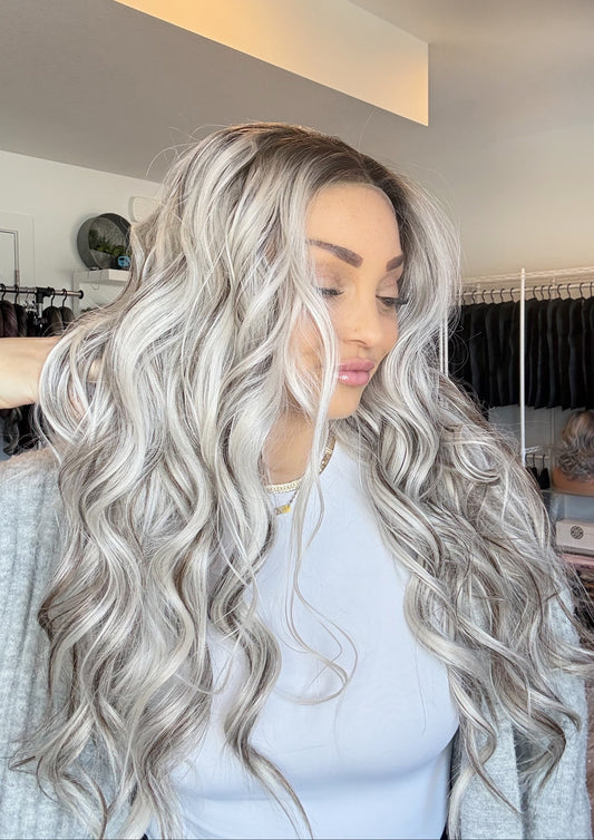 Woman with long, wavy, silver-colored hair in a salon setting.