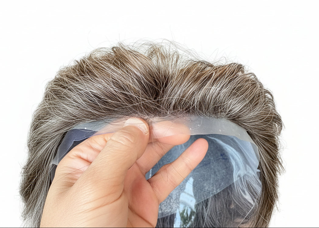 Close-up of a hand holding a section of brown hair extensions with a blurred background.