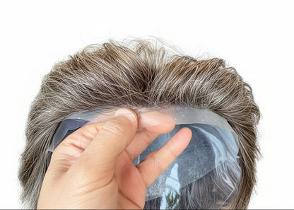 Close-up of a hand holding a section of brown hair extensions with a blurred background.
