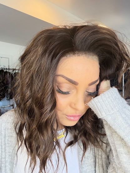 Woman with styled hair in a room with clothing racks.