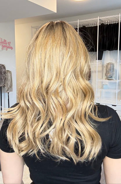 Blonde hair extensions held by a person in a salon setting