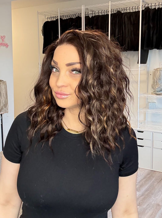 Woman with curly hair in a black t-shirt standing in a clothing store.