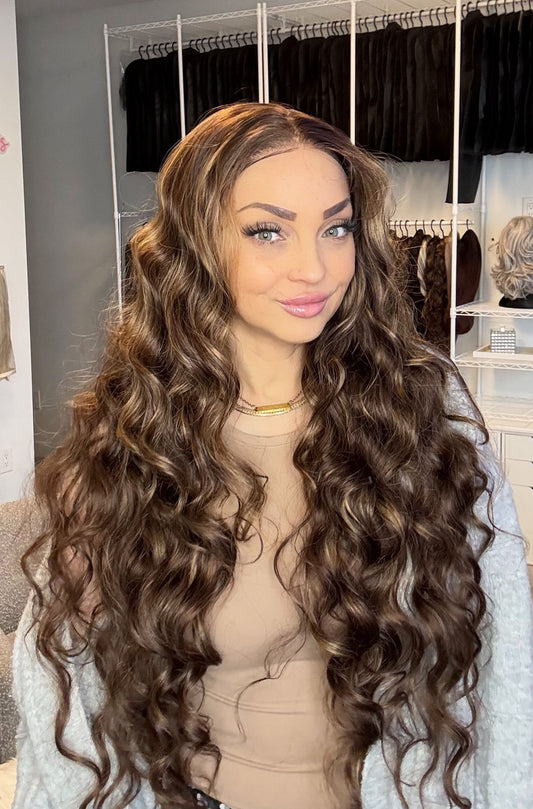 Person with long, wavy brown hair in a hair salon setting.