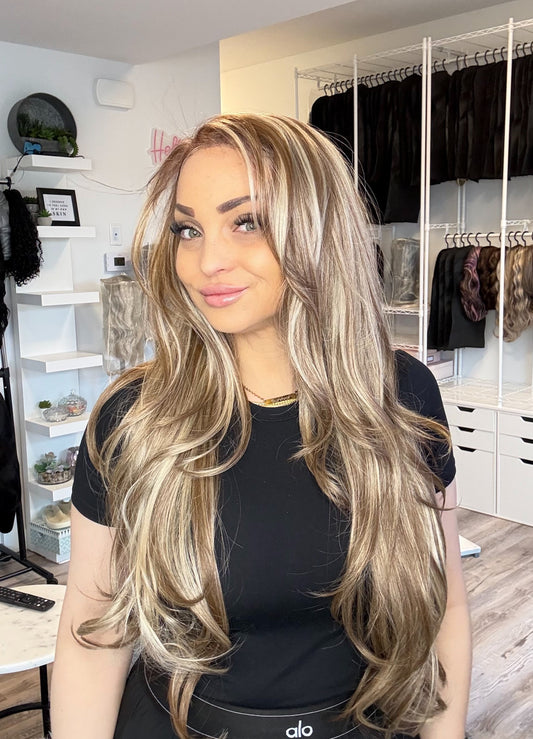 Woman with long blonde hair in a room with clothing racks and shelves.