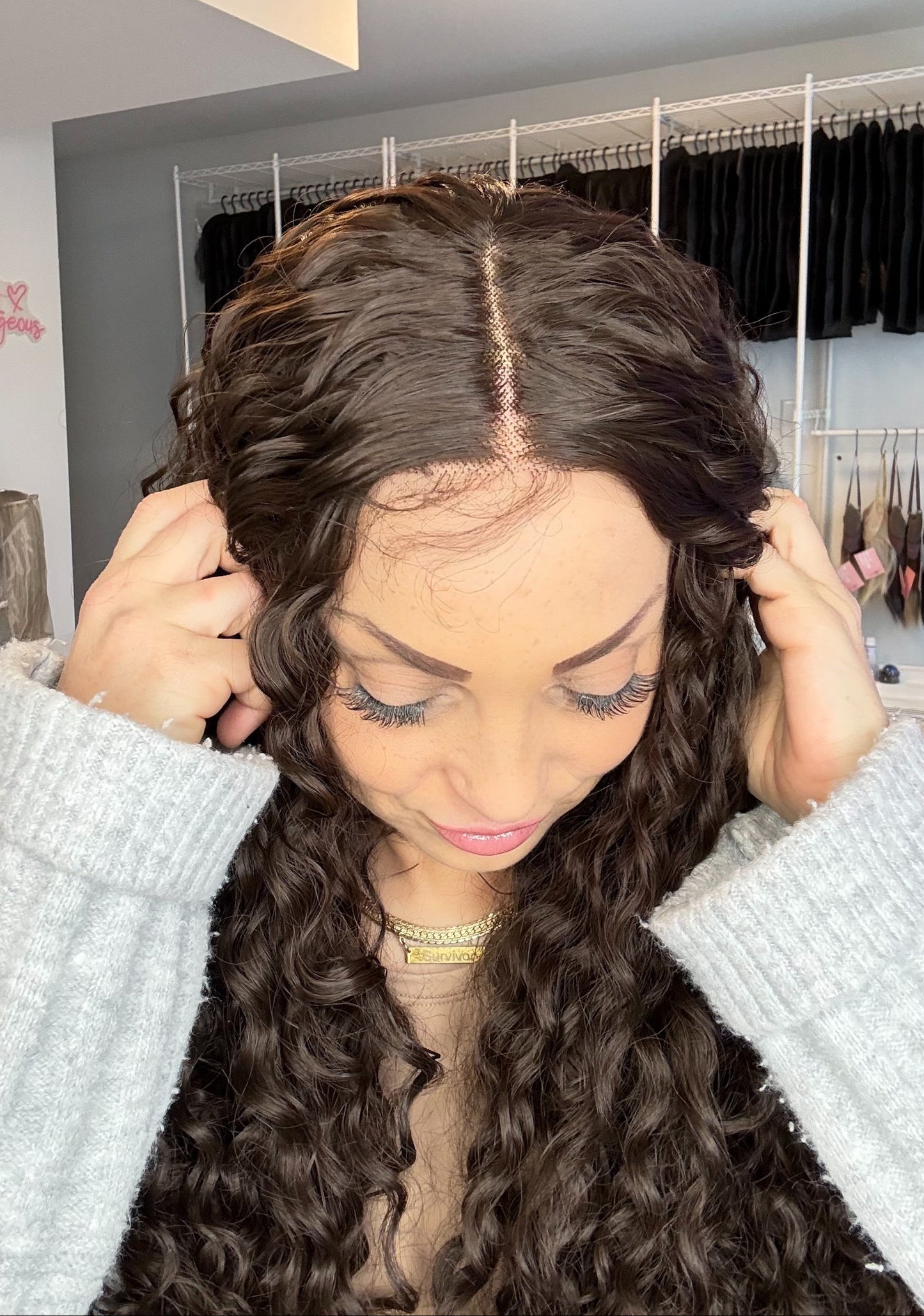 Person wearing a lace front wig in a room with clothing racks.
