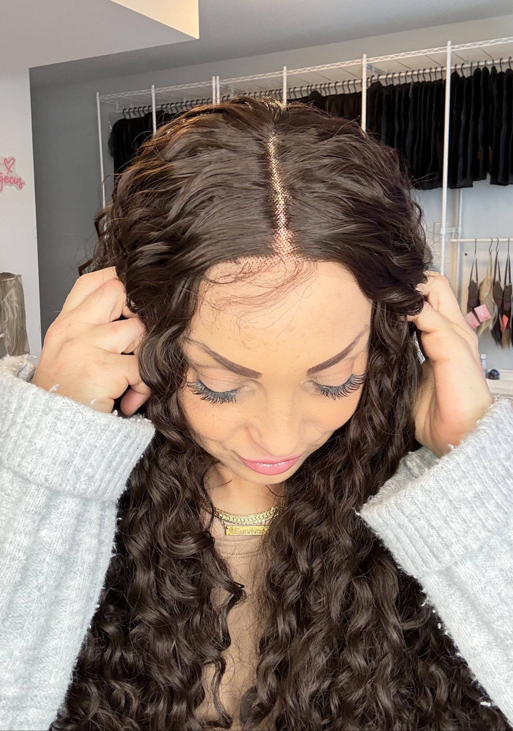 Person wearing a lace front wig in a room with clothing racks.