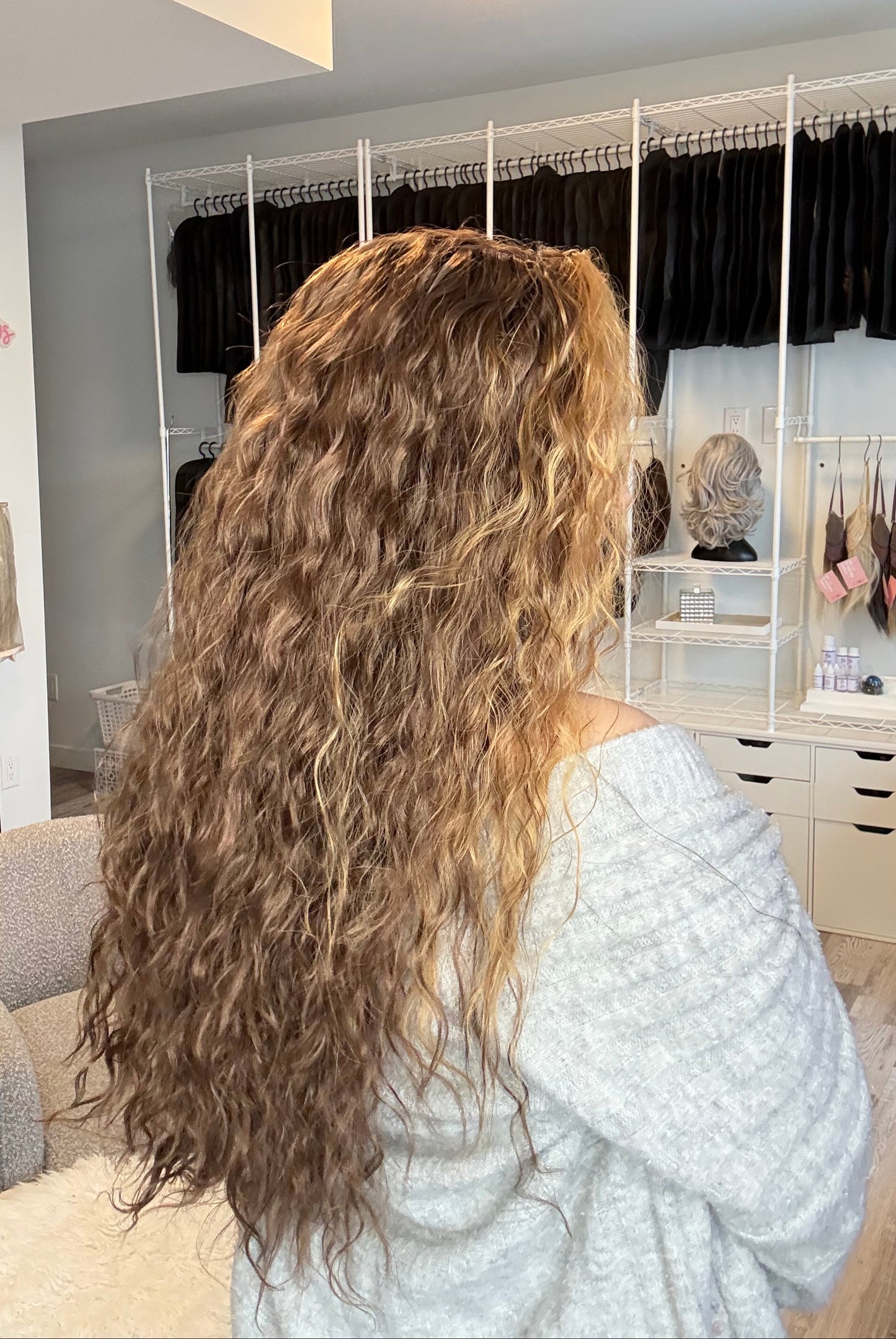 Person with long, wavy hair lying on a bed in a bedroom setting.