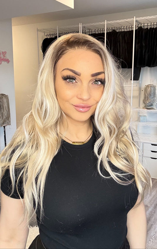 Woman with long blonde hair in a room with clothing racks and decor.