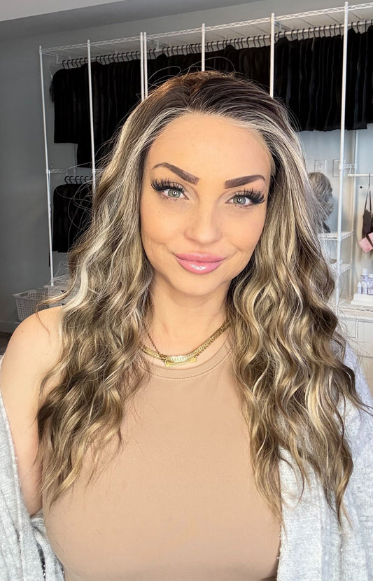 Woman with long, wavy hair in a room with a closet and various items in the background.