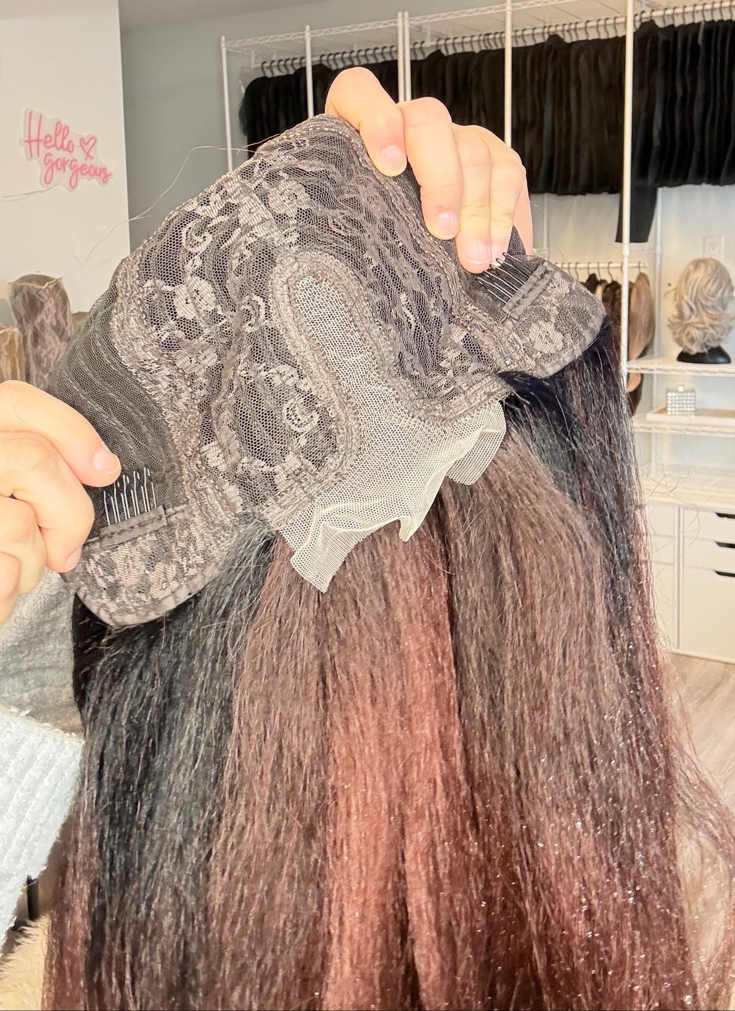 Person holding a hair extension with a lace front in a salon setting
