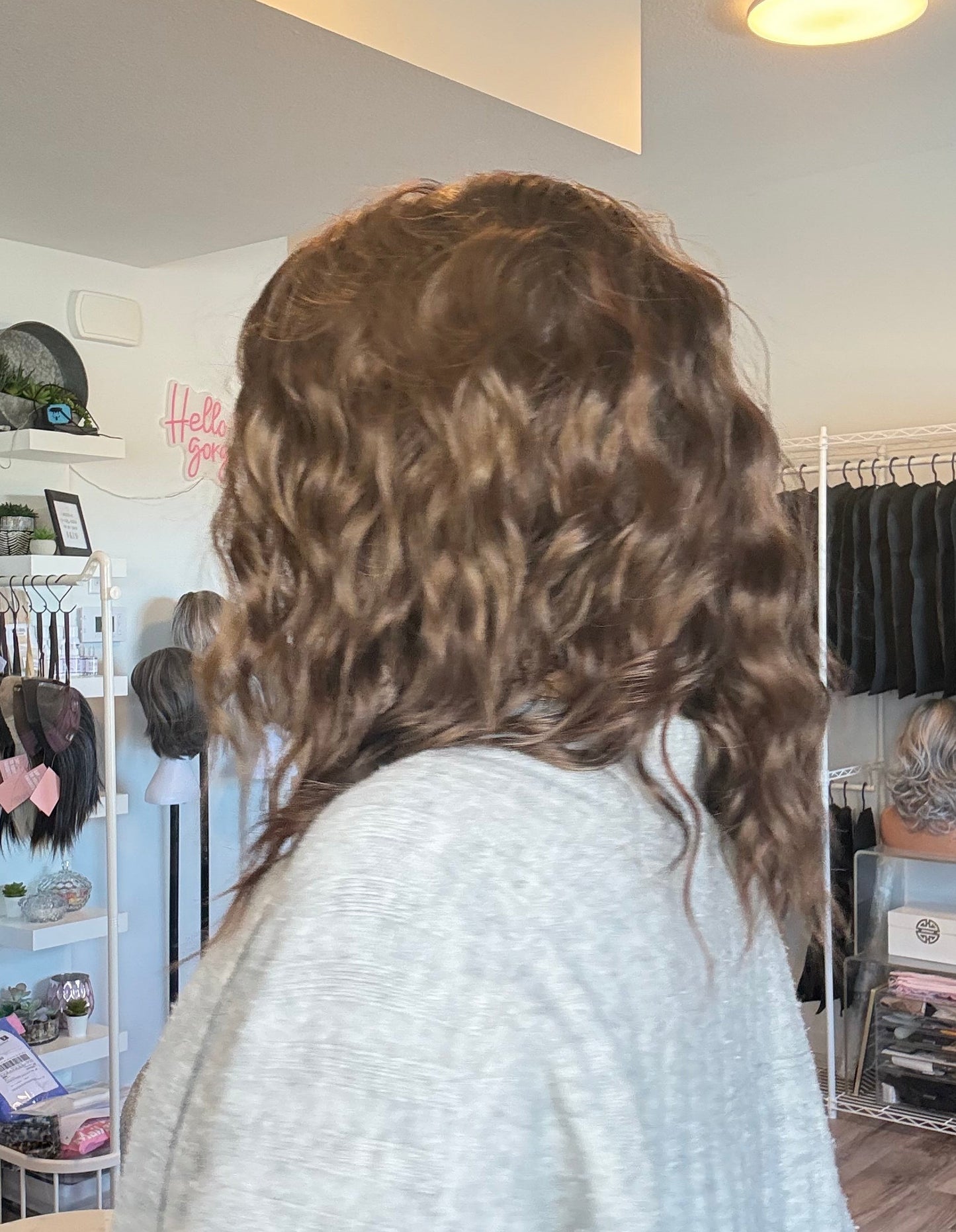 Person with curly hair standing in a room with shelves and decor.