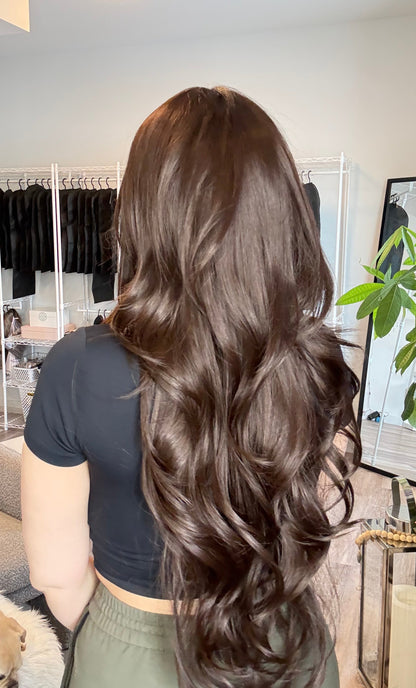 Person with styled hair in a salon setting with hair products and tools visible.