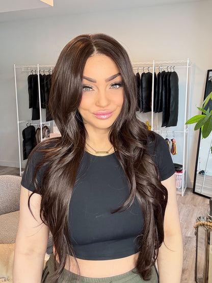 Woman with long dark hair in a room with clothing racks and decor.