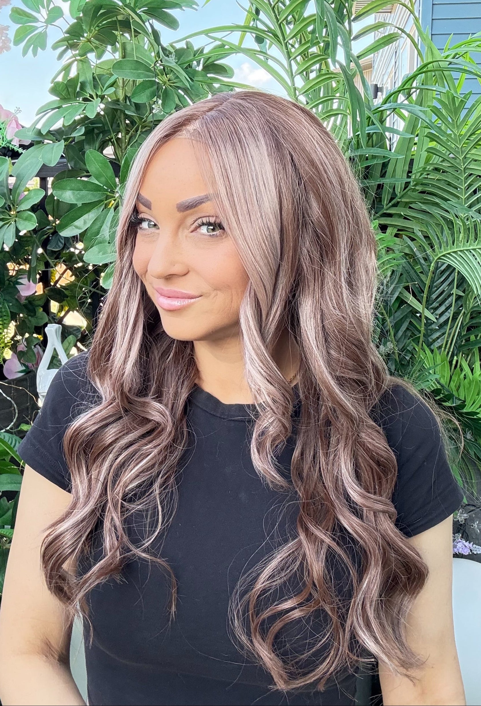 Woman with long wavy hair wearing a black top indoors.