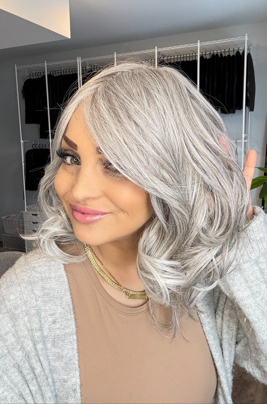 Person with silver hair in a room with clothing racks in the background