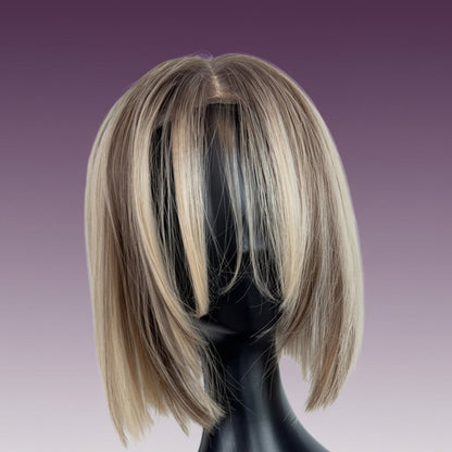 Blonde and brown bob wig on a black mannequin head against a white background
