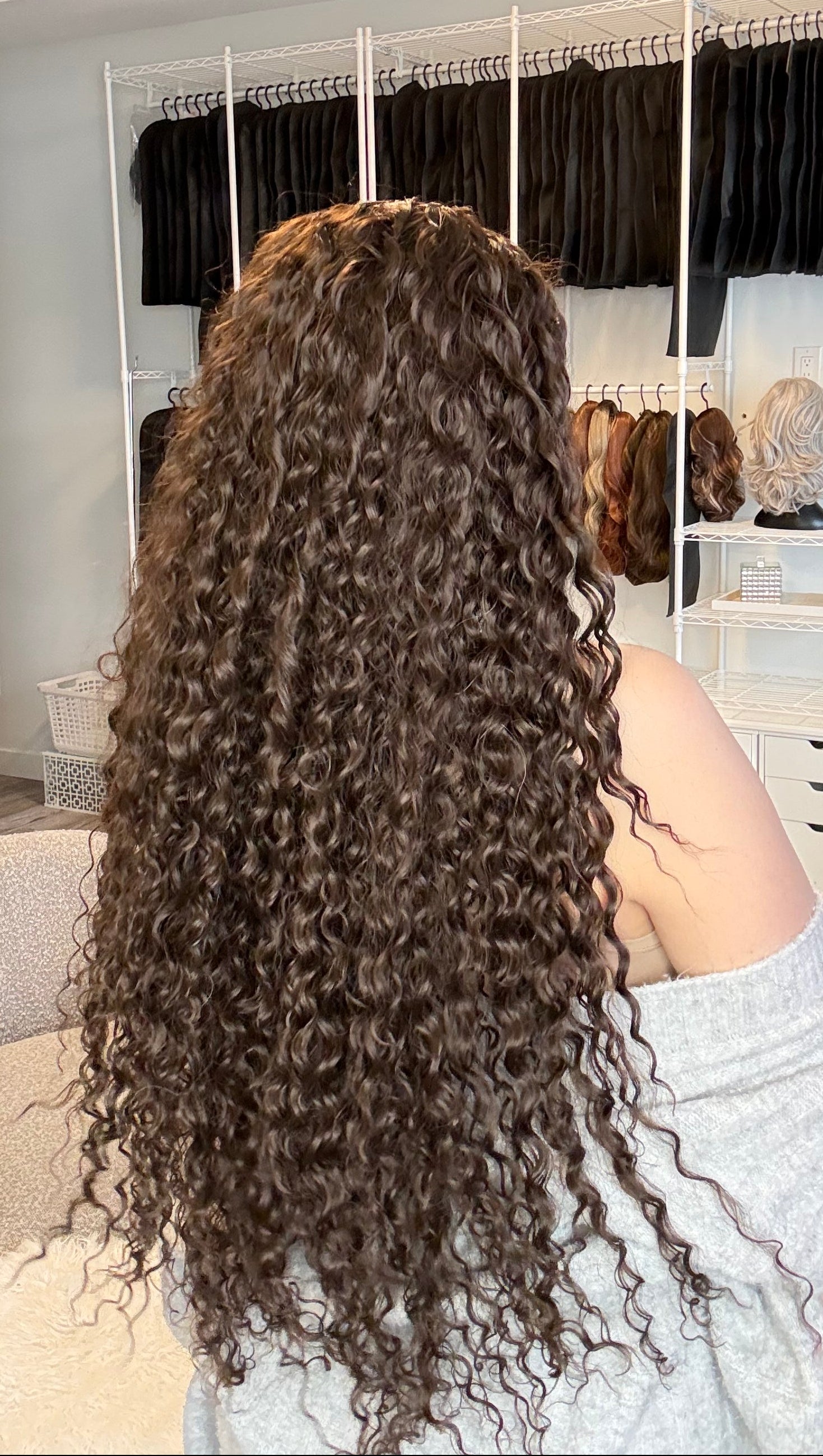 Person with styled hair in a salon setting with mirrors and hair products.