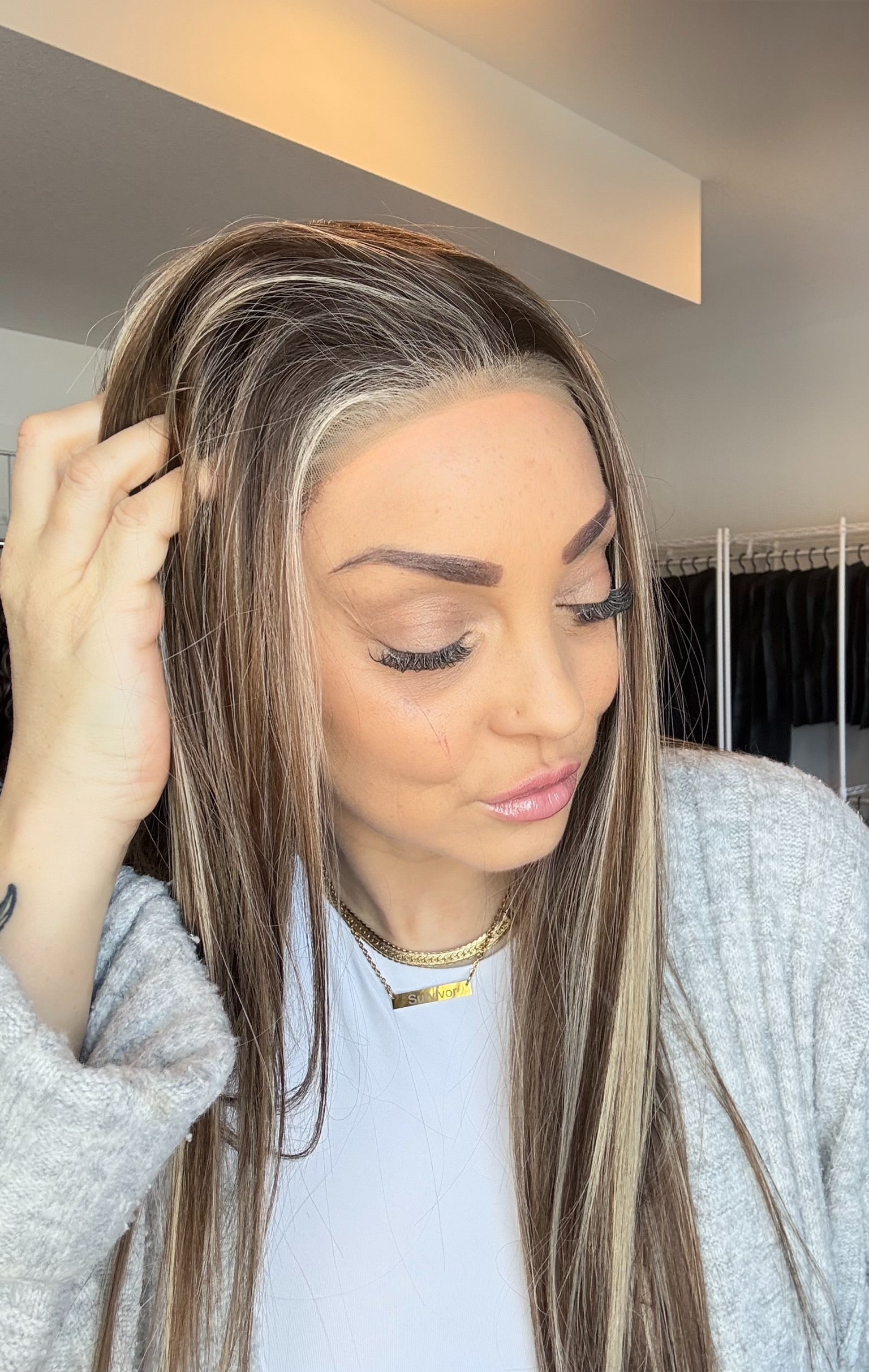 Woman adjusting a hair extension in a mirror reflection
