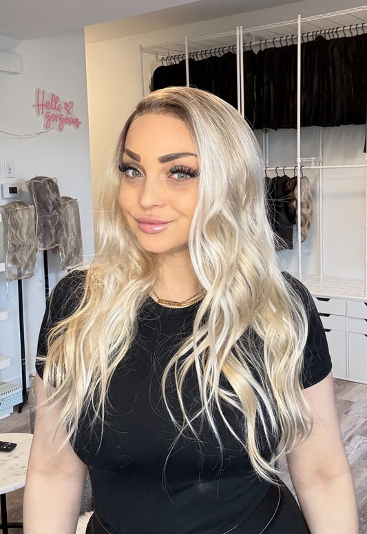 Woman with long blonde hair in a room with shelves and clothing racks.