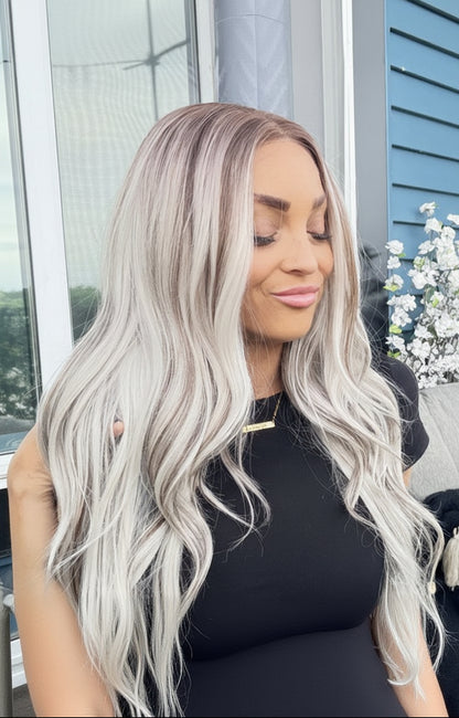 Woman with long, wavy, silver hair sitting outdoors.