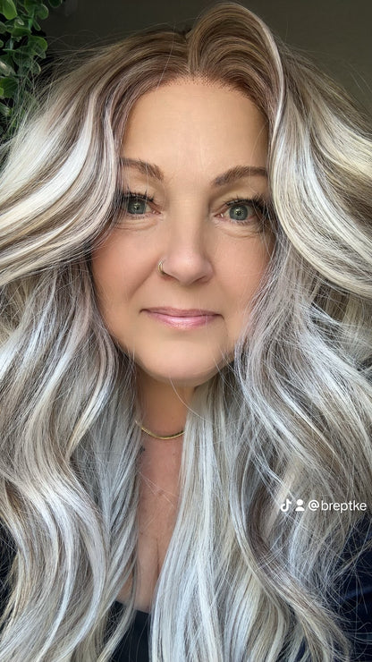 Woman with long, wavy, silver hair against a neutral background