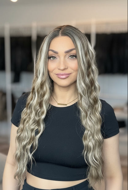 Woman with long, wavy hair standing in a room with clothing racks in the background
