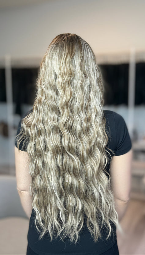 Person with long, wavy blonde hair in a salon setting