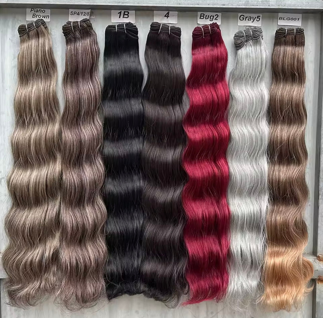 Collection of hair extensions in various colors displayed on a gray background.