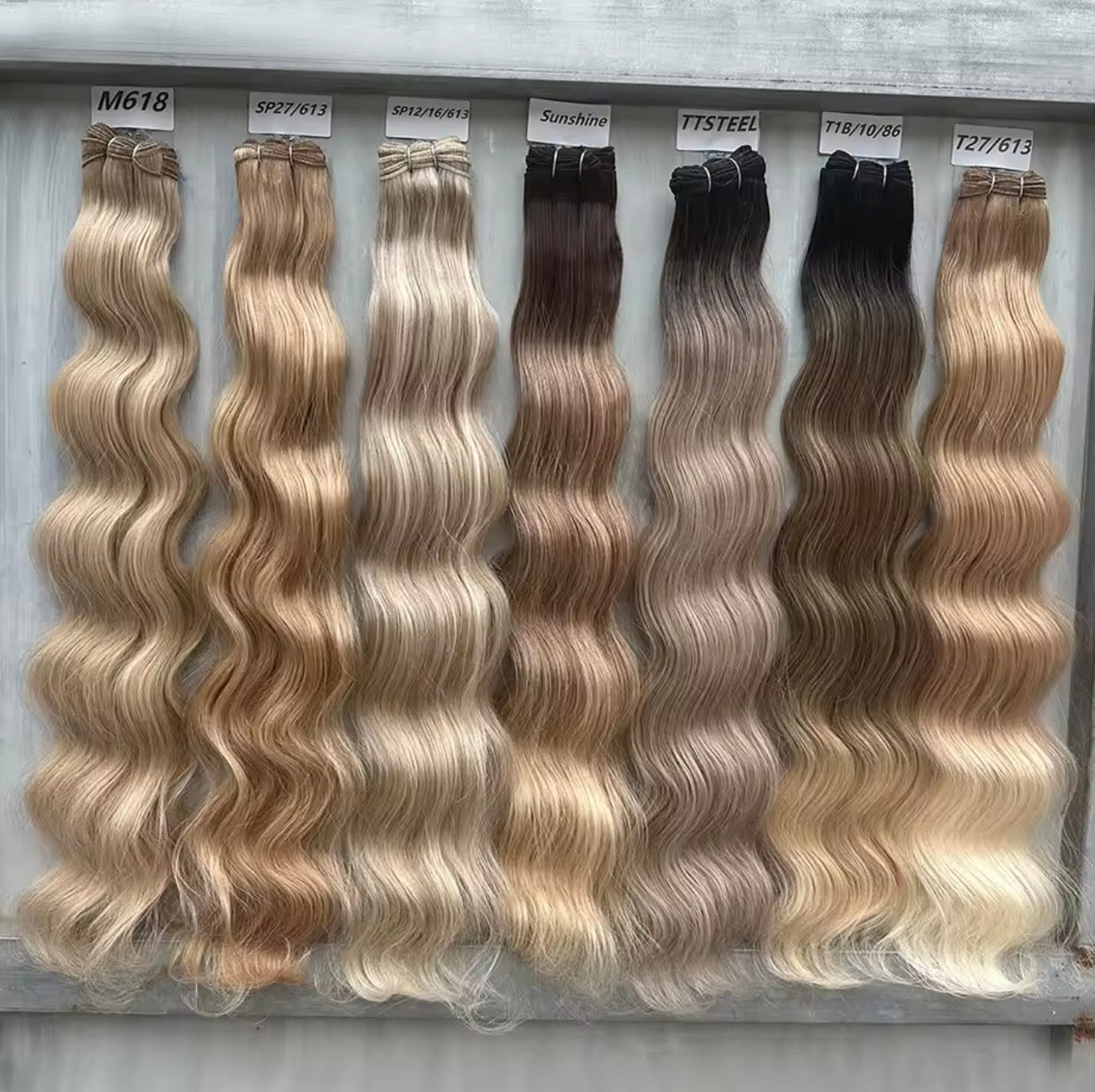 Set of hair extensions with different color shades on a gray background