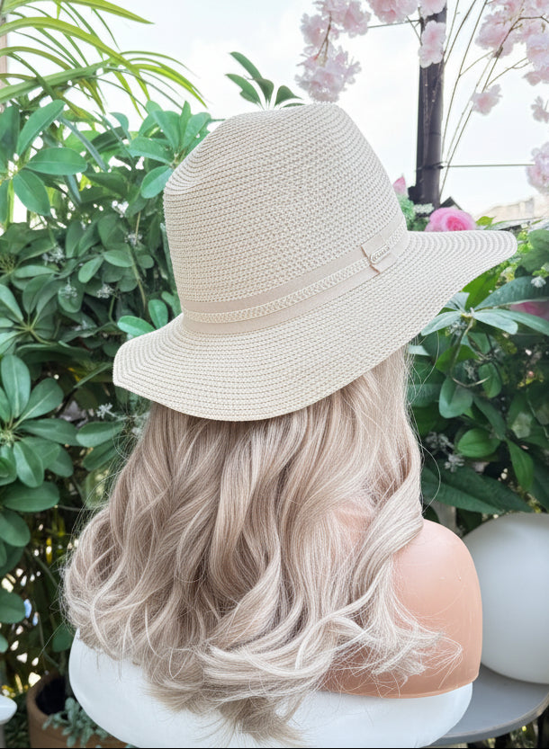 Mannequin head with blonde hair and a beige hat in a garden setting