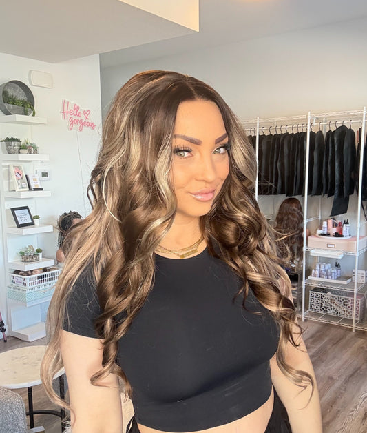 Woman with long, wavy hair in a room with clothing racks and shelves.