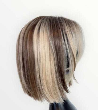 Blonde and brown wig on a mannequin head against a white background