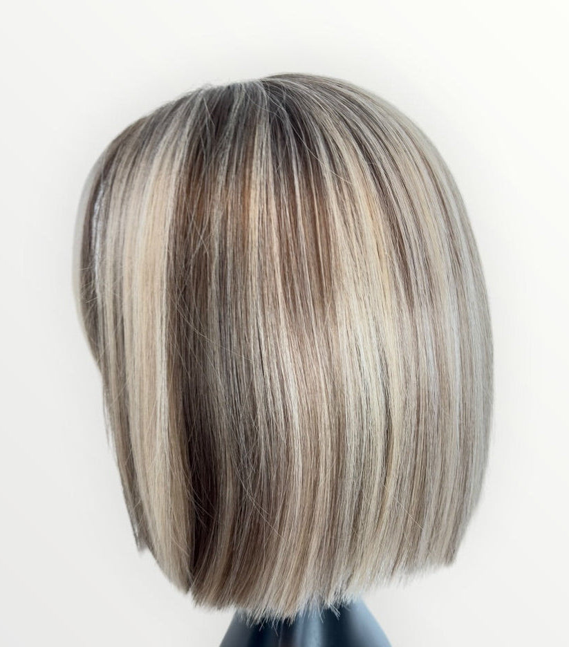 Mannequin head with a styled wig featuring brown and blonde hair on a white background