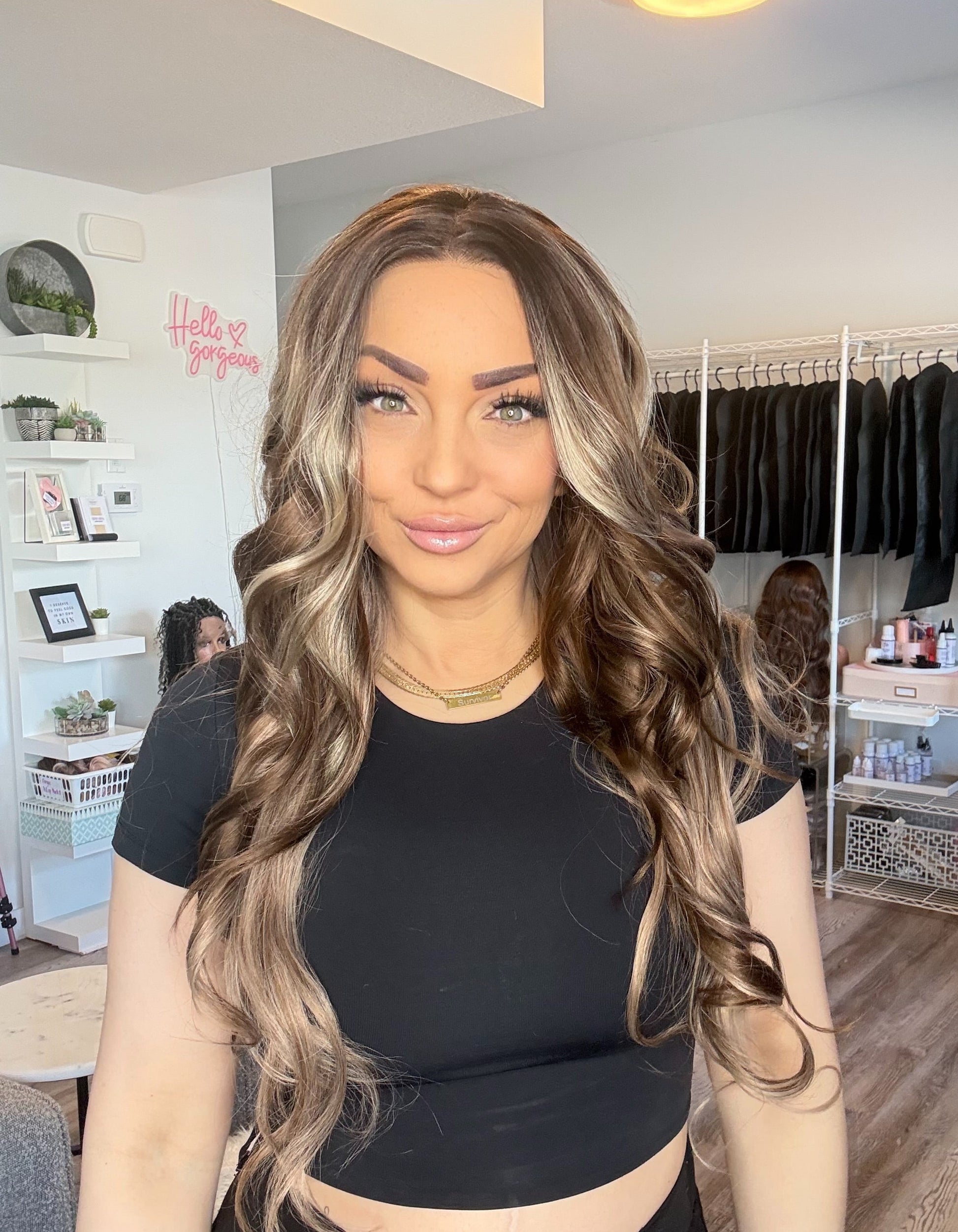 Woman with long, wavy hair in a room with clothing racks and shelves.