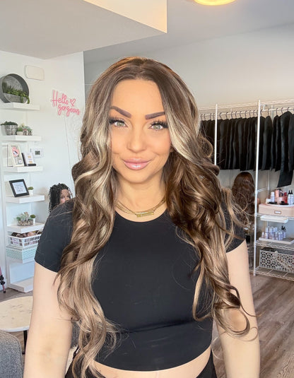 Woman with long, wavy hair in a room with clothing racks and shelves.