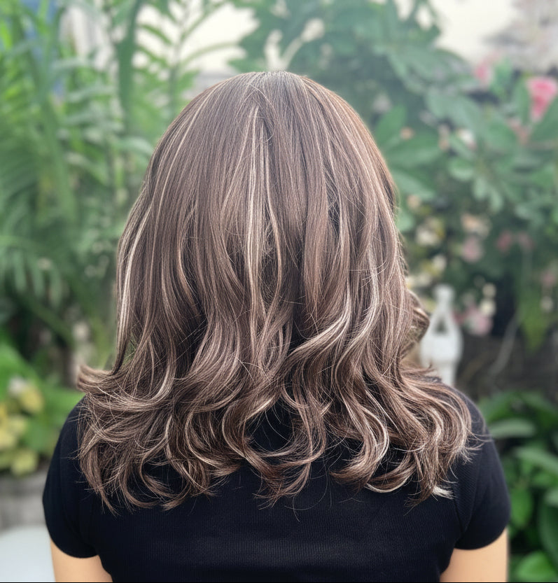 Person with styled hair in an outdoor setting with plants