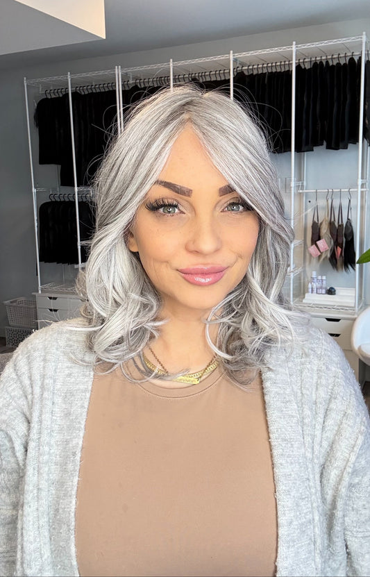 Woman with silver hair in a room with clothing racks in the background