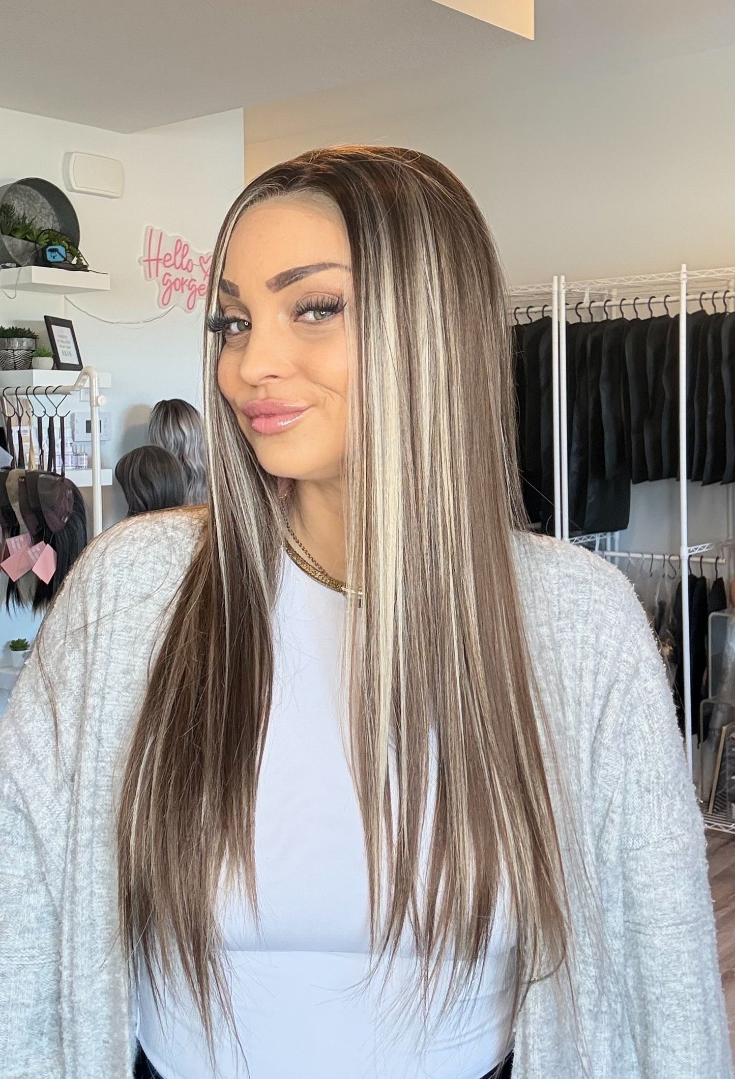 Woman with long straight hair in a room with clothing racks and mirrors.