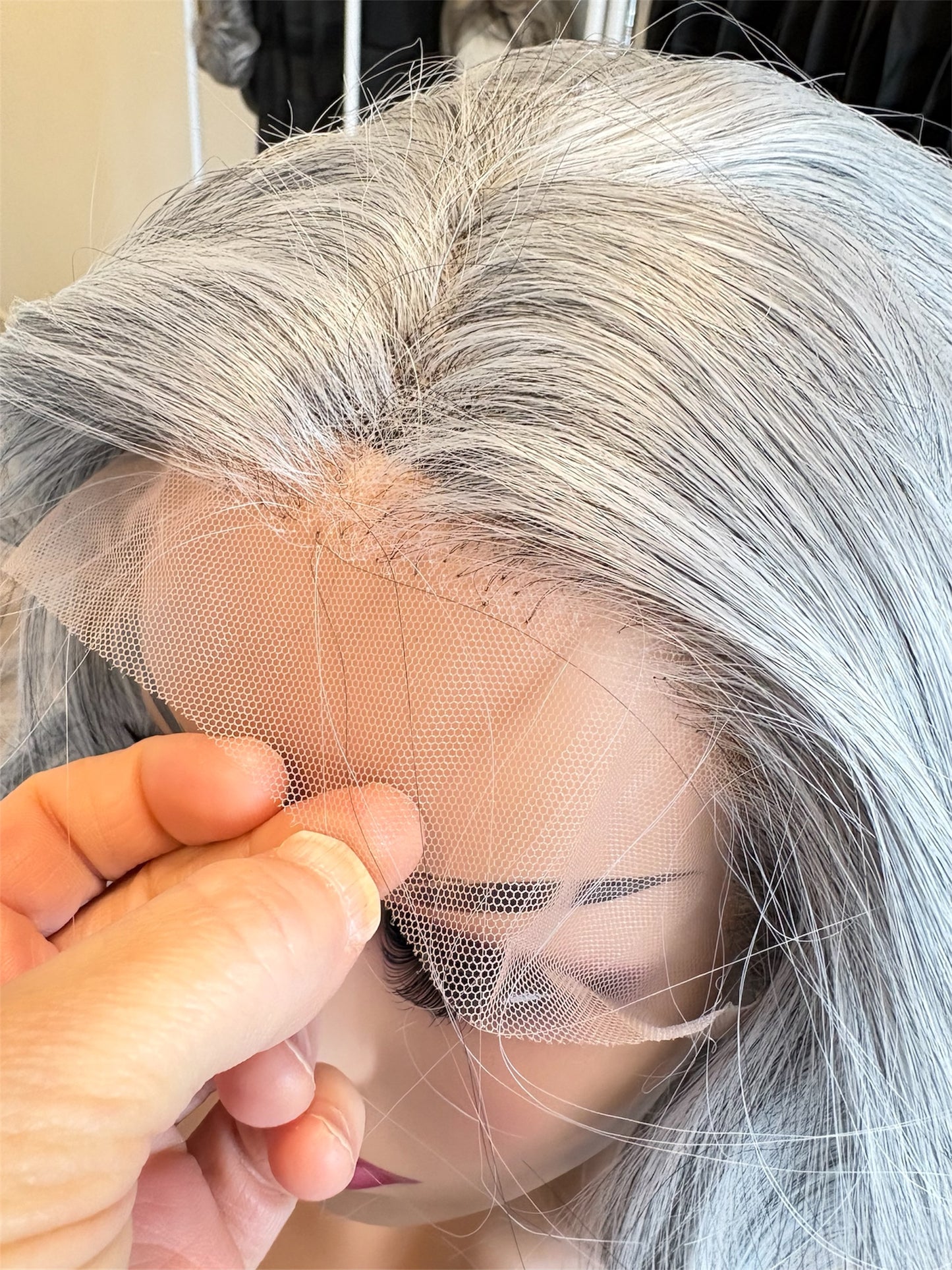 Close-up of a gray wig with a hand adjusting the mesh at the back.