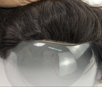 Close-up of a hairpiece held by a hand on a white background