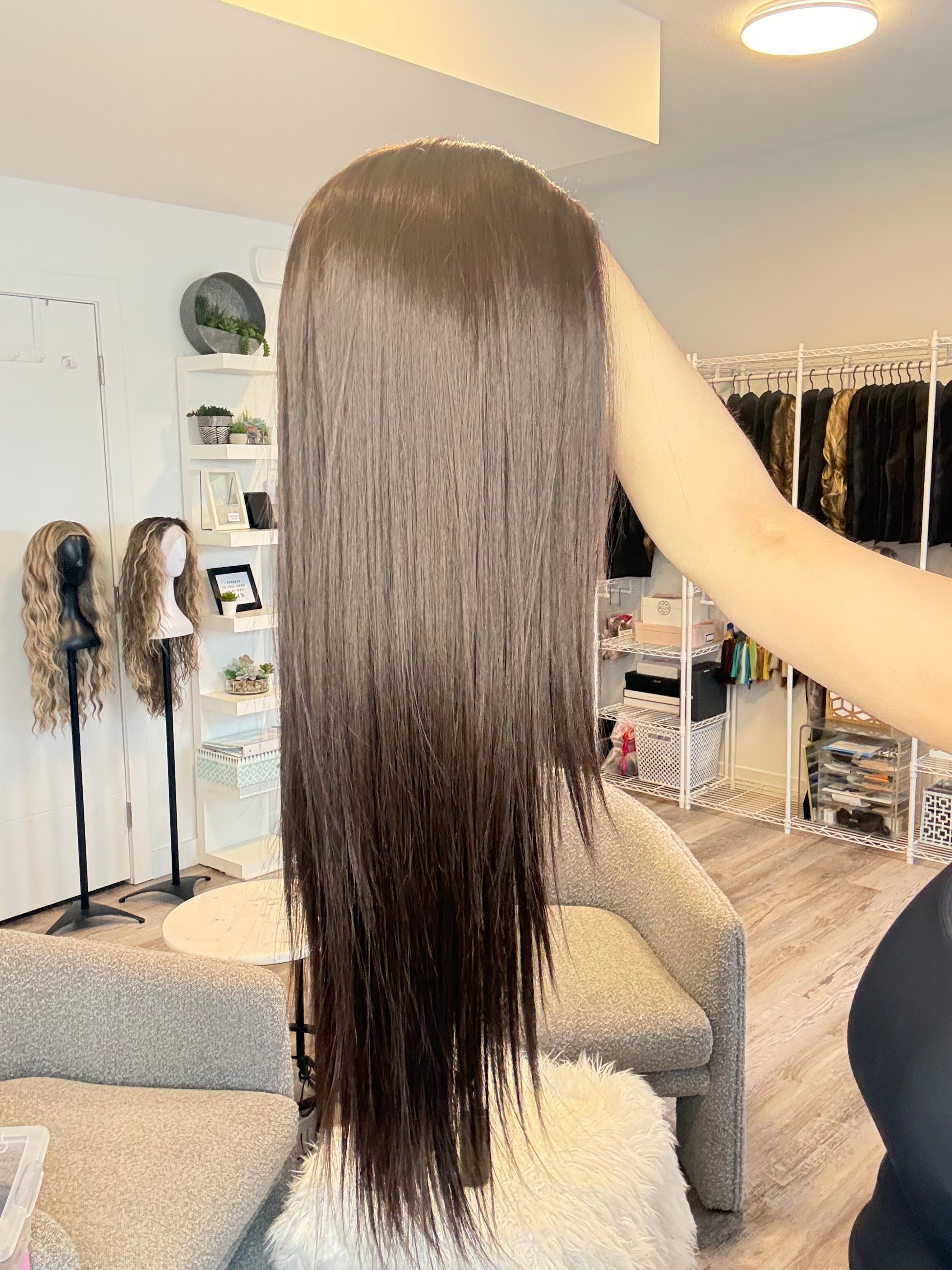 Long brown hair displayed in a salon setting with mirrors and products.