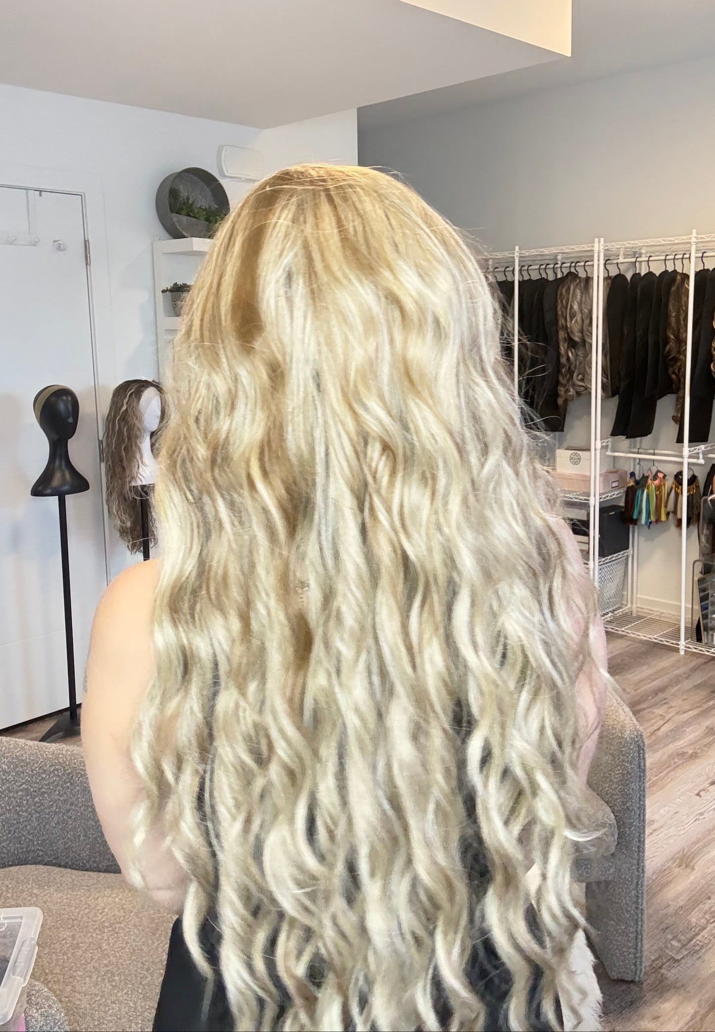 Close-up of a person with long, wavy blonde hair in a salon setting.