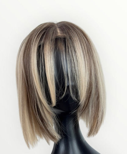 Blonde and brown bob wig on a black mannequin head against a white background