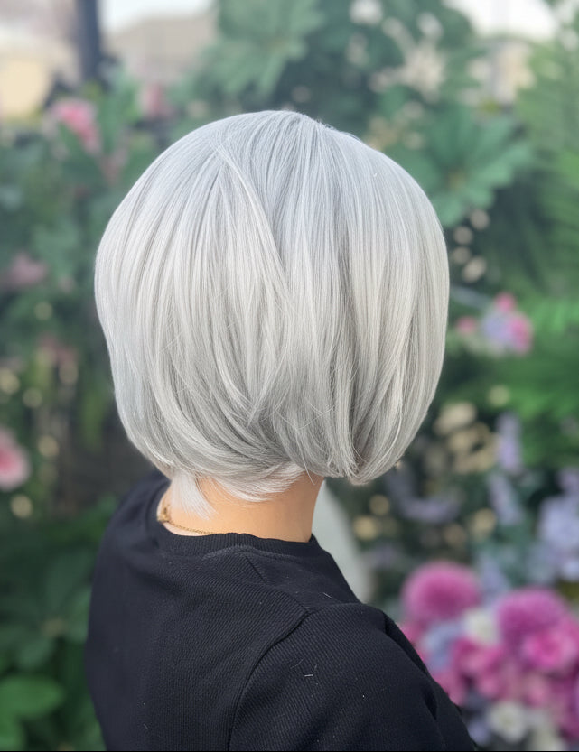 Person with gray hair sitting among flowers and plants